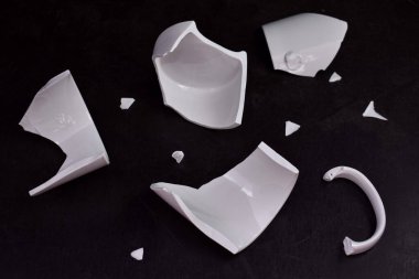 Beyaz seramik bardak parçalanmış, parçalar, siyah arka plan. Psikoloji ve felsefe için fikir.