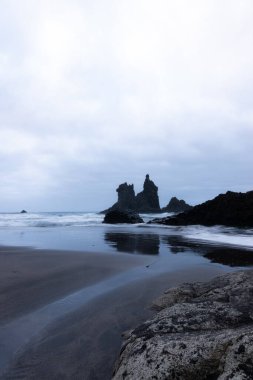 Bulutlu bir günde sahilde korkunç bir kaya.