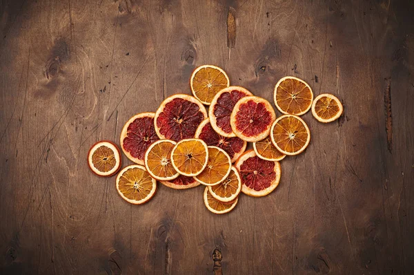 Heap of dried orange and grapefruit rings on dark brown vintage rustic wooden background. Top view with copy space