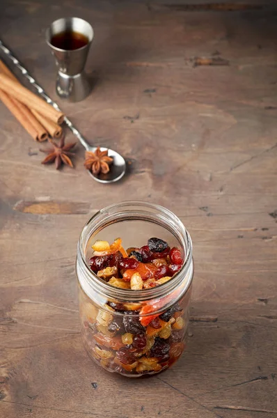 Mixed dry fruits and candied orange peel soaked with spices in rum for traditional Christmas Fruit Cake. Close up view on a vintage wooden background