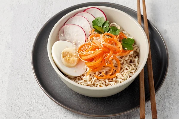Bowl of veggie noodle broth ramen with egg, carrot, radish and s