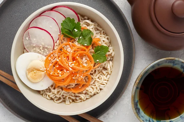 Bowl of veggie noodle broth ramen with egg, carrot, radish and s