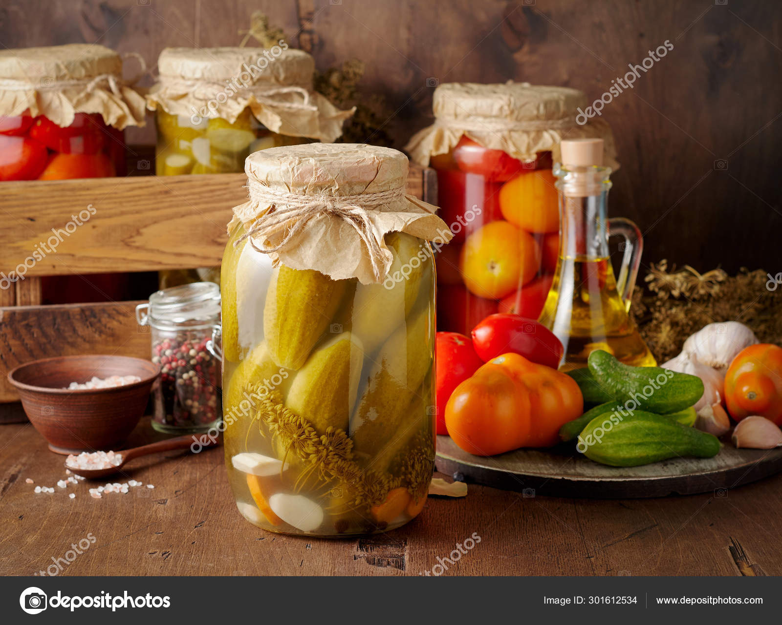 Homemade pickled tomato and cucumber in glass jars on an wooden Stock