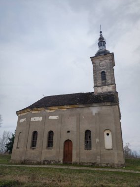 Bulutlu bir günde kasvetli bir gökyüzüne karşı harap durumda terk edilmiş eski bir kilise binası. Dini yapı üzerine çatlamış ve soyulmuş cephe.