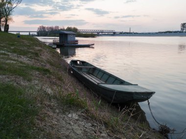Bulutlu bir akşamda Bosanski Brod 'daki Sava Nehri' nin kıyıda demirli balıkçı tekneleriyle manzarası. Bosanski Brod, Bosna-Hersek.