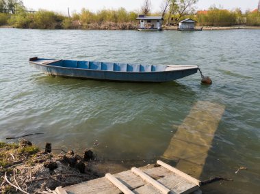 Güneşli bir günde Sava Nehri 'nin kıyısındaki rıhtımın yanında demirlemiş bir tekne. Bosanski Brod, Bosna-Hersek.