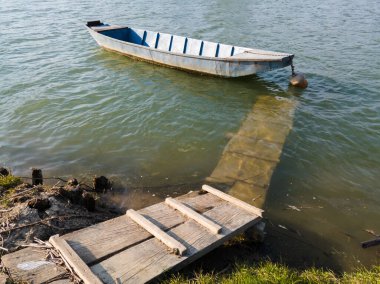 Güneşli bir günde Sava nehrinin rıhtımında demirli bir tekne. Bosanski Brod, Bosna-Hersek.
