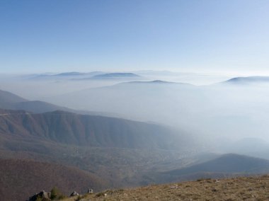 Sonbaharda güneşli bir günde, Vlasiç dağından vadinin sisli ve dağ zirveleriyle dolu manzarası.