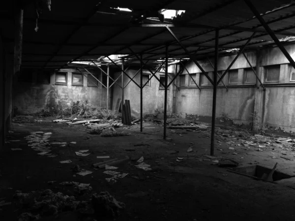 Terk edilmiş, boş, sütunları kırık asbest levhalarla çatıyı destekleyen boş bir oda..