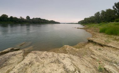 Kasvetli ve yağmurlu bir yaz günü, Bosanski Brod 'daki kayalık kıyı ve ormanları ve petrol rafinerisinin sanayi fabrikasıyla Sava nehrinin panoramik manzarası.