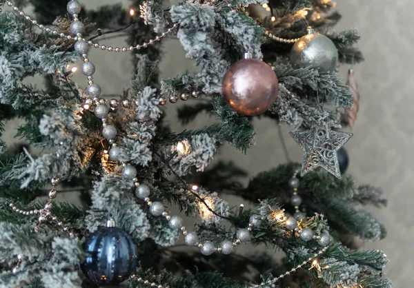 别致的圣诞树装饰 粉色和银色装饰 有选择的重点 圣诞树枝头铺满了雪 点缀着灯 球和花环 特写装饰 节日的精神 新年背景 — 图库照片