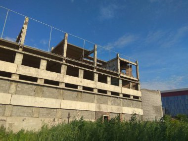  Rusya-Krasnoyarsk. 30 Haziran 20.Gri renkli beton bina. Arka planda modern bina ile tamamlanmamış yapılar
