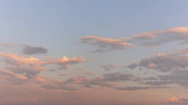 Gün batımında mavi gökyüzünde yüzen pek çok küçük beyaz bulut. Kabarık bulutlu arkaplan