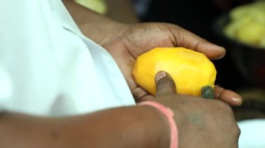Küçük bir bıçakla mango kesen adam..