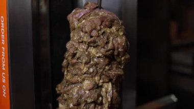 Sokak lokantasında dönen bir shawarma makinesinin tavuğunu kesmek..