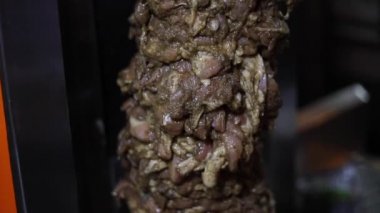 Sokak lokantasında dönen bir shawarma makinesinin tavuğunu kesmek..
