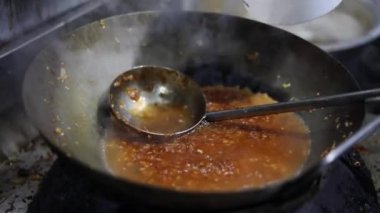 Tibetli anneler ve börekler için Hint tavasında kırmızı turşu sosu pişirmek. Kızarmış soğan, tuzlu ve diğer baharatlarla..