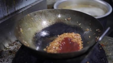 Tibetli anneler ve börekler için Hint tavasında kırmızı turşu sosu pişirmek. Kızarmış soğan, tuzlu ve diğer baharatlarla..
