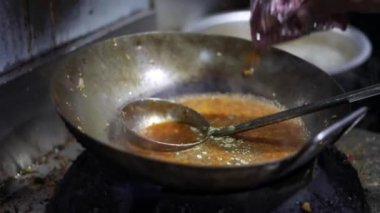 Tibetli anneler ve börekler için Hint tavasında kırmızı turşu sosu pişirmek. Kızarmış soğan, tuzlu ve diğer baharatlarla..