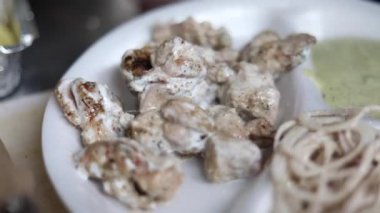 Kağıt tabakta soğan ve nane aromalı Malai tikka tabağı. 