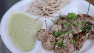 Kağıt tabakta soğan ve nane aromalı Malai tikka tabağı. 