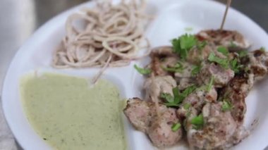 Kağıt tabakta soğan ve nane aromalı Malai tikka tabağı. 