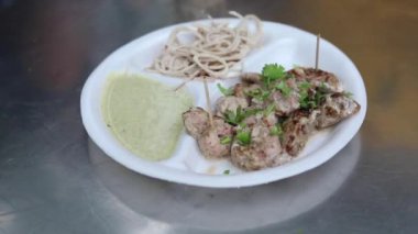 Kağıt tabakta soğan ve nane aromalı Malai tikka tabağı. 