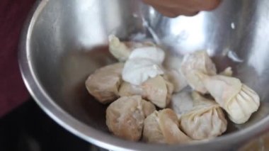 Afgan buğulanmış tavuk momo 'ları krema ve baharatla marine edilmiş soğan, kırmızı baharatlı sos ve yeşil nane sosuyla servis ediliyor..