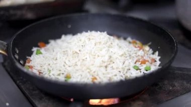 Siyah bir tavada kişniş ile süslenmiş beyaz pirinç pişiriyorum..