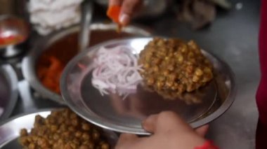 Soğan, kızılderili salatası ve bezelye ile sunulan choley bhature sosu..