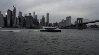 New York şehrinin siluetinin önündeki nehirde yelken açan yat ya da gemi..