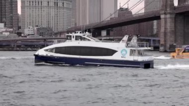 New York şehrinin siluetinin önündeki nehirde yelken açan yat ya da gemi..