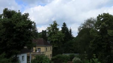 Avrupa 'da ağaçlarla çevrili bir evin üzerinde bulutların hızlanması.