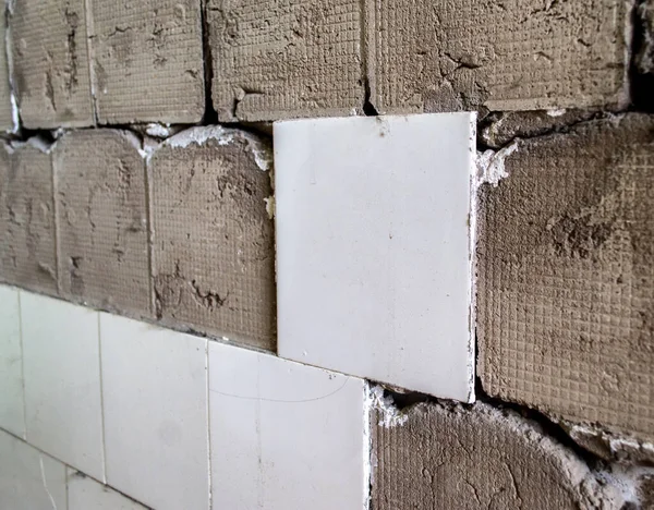 repair of wall tiles. partially knocked down tile. removing old tiles from the wall