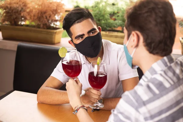 gay couple in restaurant wearing masks. social distancing, restaurants reopening