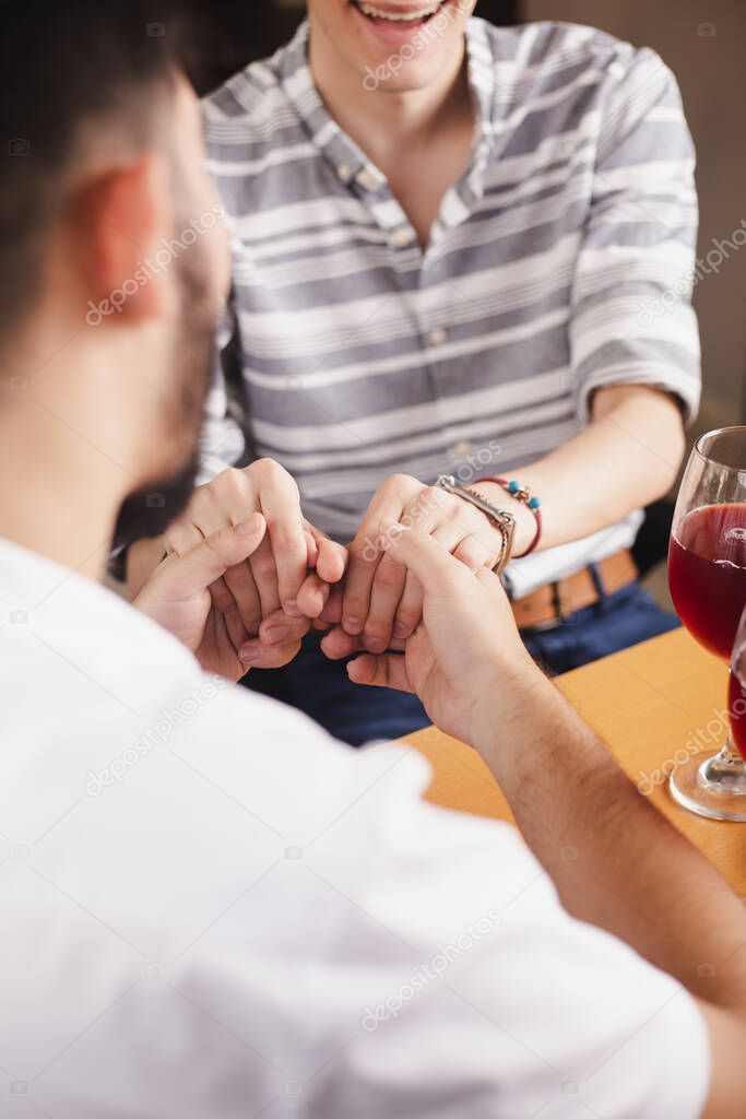 Gay couple shaking hands on a romantic date in restaurant