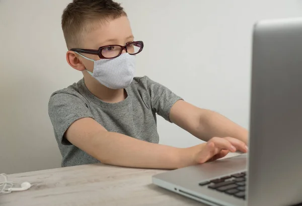 Gri tişörtlü bir çocuk dizüstü bilgisayarın başına oturur ve internete bağlanır, uzaktan öğrenme, dizüstü bilgisayarın başındaki bir çocuk dizüstü bilgisayara bakar. Yüksek kalite fotoğraf — Stok fotoğraf