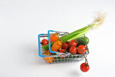 Sepette sebzeler, beyaz arka planda market arabası metali. Yemek sepeti konsepti. Kapatın. Düz Yat. Seçici yumuşak odaklanma. Yüzeyin derinliği. Metin kopyalama alanı.
