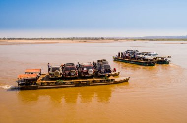 Turistler ve off-road araçları el yapımı feribotlarla Tsiribihina nehrinden geçiyorlar.