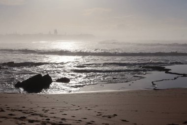 Güneşin altında dalgalı suyla parlayan denizin arka plan görüntüsü. Islak sahil ve yansıtan güneş ışığı.