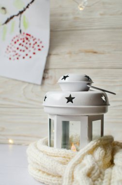 Ahşap zemin üzerine beyaz eşarp sarılı rahat beyaz fener, dekore edilmiş sarı ışıklar ve kırmızı-rowan dal resmi 