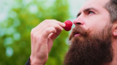 Tatlı çilek yeme genç bir adam. adam cinsel bir oyunun bir parçası bir çilek yeme. Çilek tutarak ve gülümseyen genç adam.