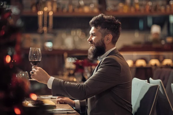 Gülümseyen ve bulanık arka plan üzerinde kırmızı şarap tutan yakışıklı genç adam portresi.