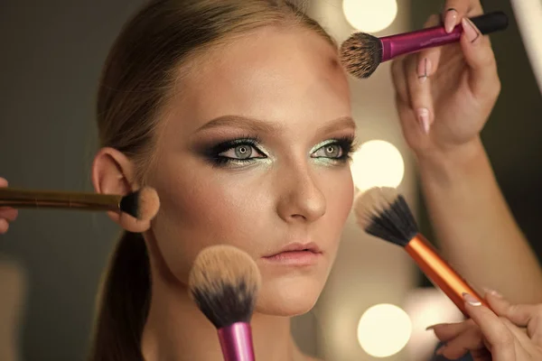 Beautiful young woman with makeup brushes around face. — Stock Photo, Image