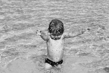 Islak saçlı şirin bebek çocuk su havuzunda sprinkles.