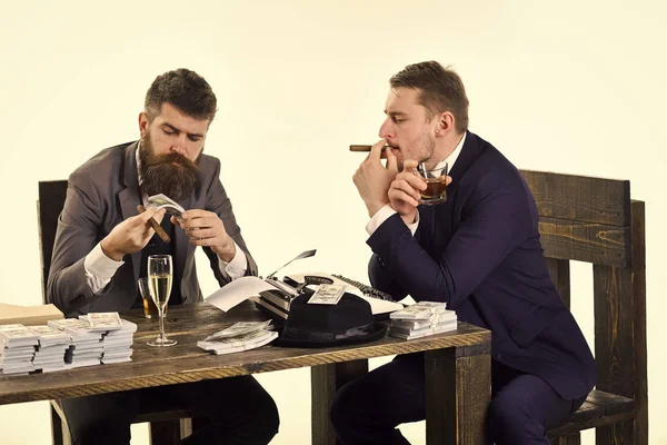 Company engaged in illegal business. Men sitting at table with piles of money and typewriter. Illegal business concept. Businessmen discussing illegal deal while drinking and smoking, white background