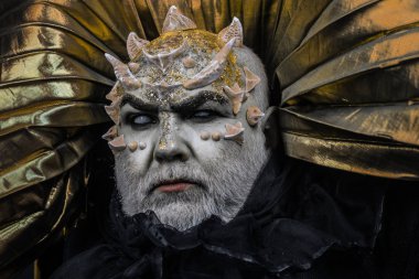 Adam dikenler veya siğiller ile yüz pırıltılar ile kaplı. Şeytan siyah zemin üzerine altın yakalı. Uzaylı, iblis büyücü makyaj. Fantezi kavramı. Beyaz sakallı komuta sizde canavar gibi giyinmiş.