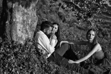 Sakallı adam ve iki kadınla çimenlerin üzerinde