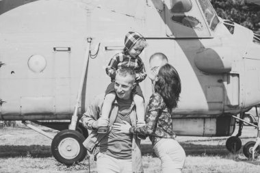 Anne ve baba ve çocuklarının Havacılık Müzesi havada yürüyüş. Mutlu aile zaman harcamak birlikte, gezi, helikopter veya uçak arka planda, güneşli bir gün. Yetiştirme ve geliştirme kavramı