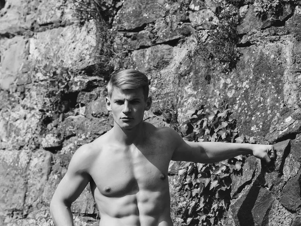 Erkek vücut bakımı iyileştiriyor. Taşlı duvar zemin üzerinde kas adam